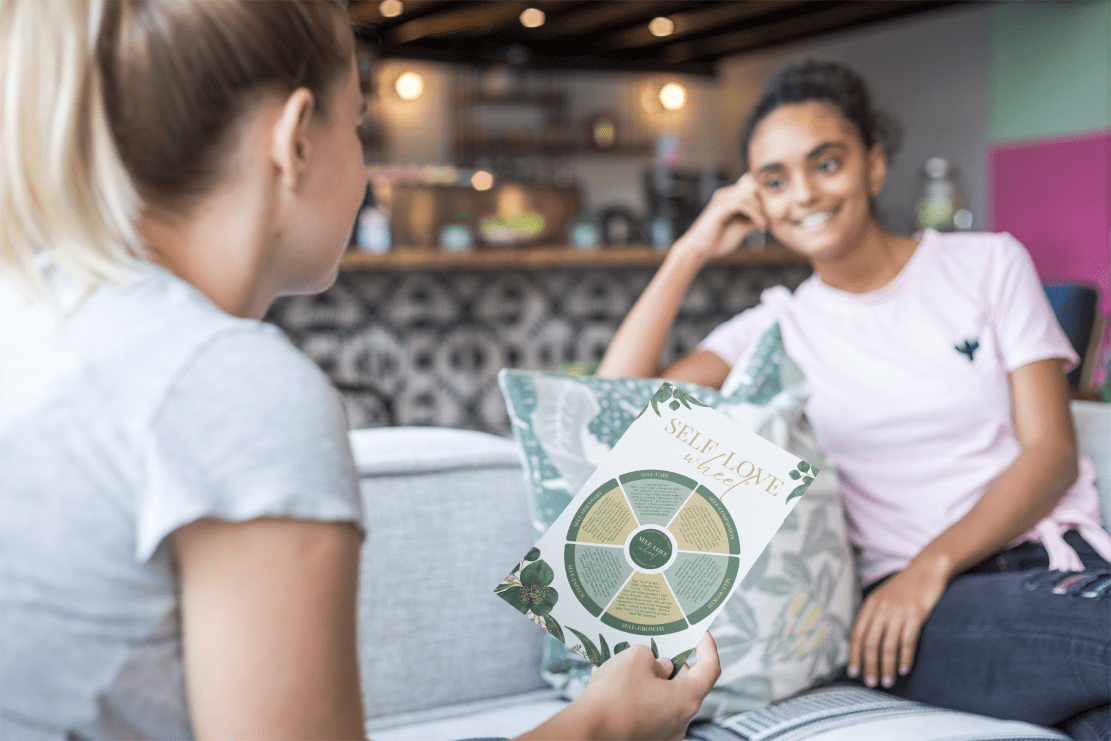 Two women discussing the Self-Love Wheel